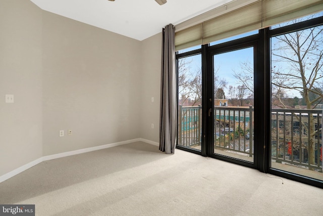 carpeted spare room featuring baseboards and a ceiling fan