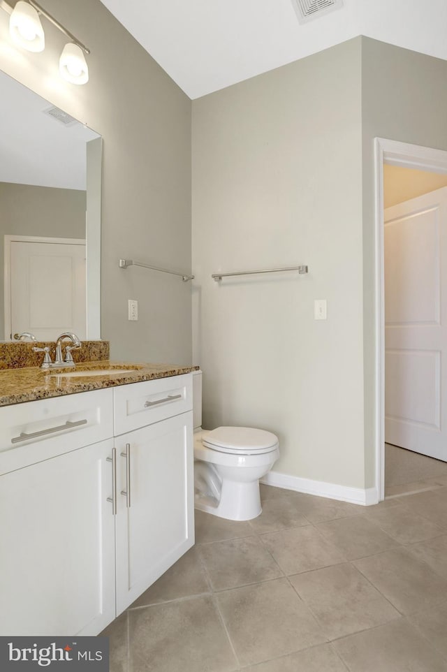 bathroom featuring visible vents, toilet, vanity, baseboards, and tile patterned floors