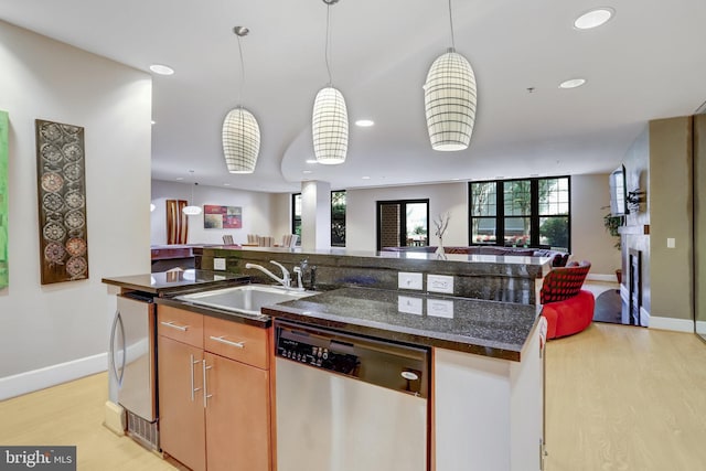 kitchen with a sink, light wood-type flooring, open floor plan, and dishwasher