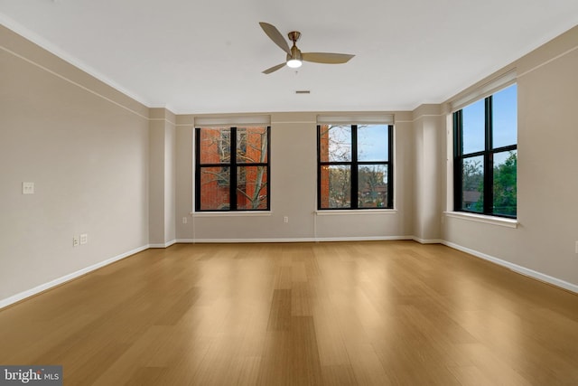 spare room featuring a ceiling fan, baseboards, and wood finished floors