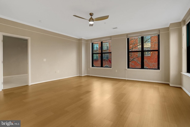 spare room featuring wood finished floors, a ceiling fan, and baseboards