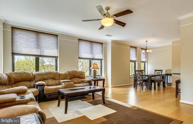 living area featuring a wealth of natural light, wood finished floors, visible vents, and crown molding