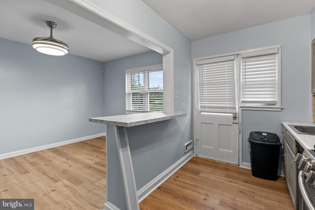 interior space featuring a sink, baseboards, and light wood finished floors