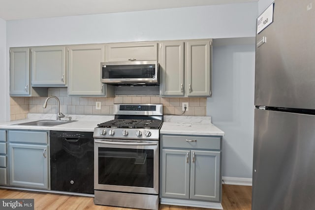 kitchen with light countertops, a sink, gray cabinets, and stainless steel appliances