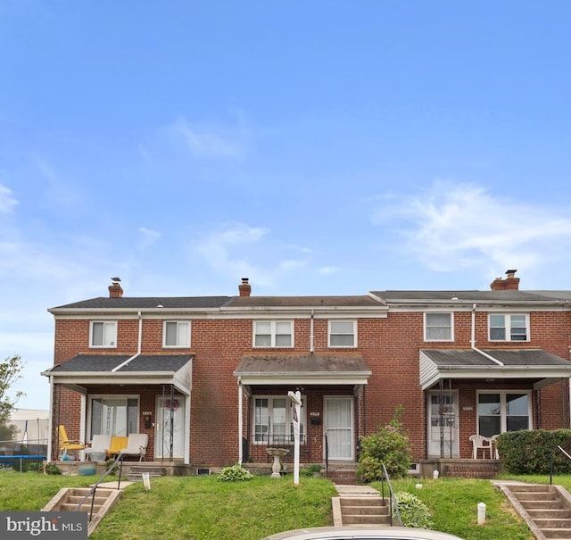view of front of house with a chimney, a front lawn, and brick siding