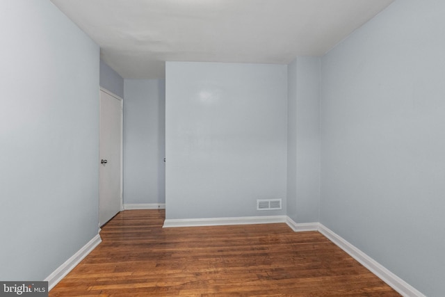 empty room featuring baseboards, wood finished floors, and visible vents
