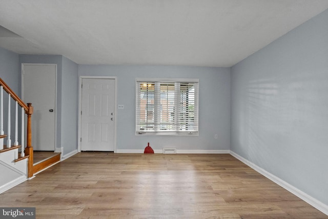entryway with baseboards, wood finished floors, and stairway