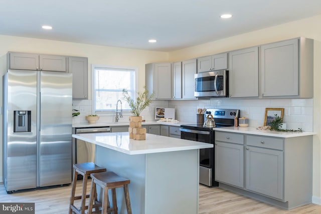 kitchen featuring stainless steel appliances, light wood-style floors, a breakfast bar area, and gray cabinetry