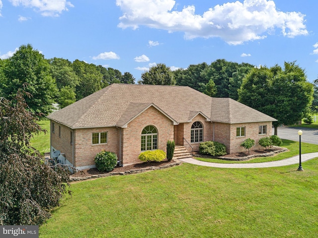 ranch-style home featuring brick siding, roof with shingles, and a front yard