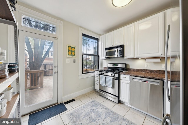 1619 Marion St NW, Washington, DC 20001 - kitchen with appliances with stainless steel finishes, white cabinets, light tile patterned floors, baseboards, and dark stone counters