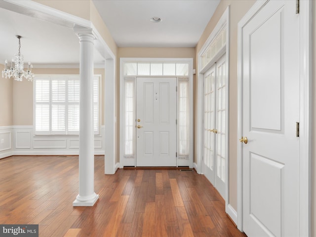 entrance foyer with a wainscoted wall, wood-type flooring, decorative columns, and a decorative wall