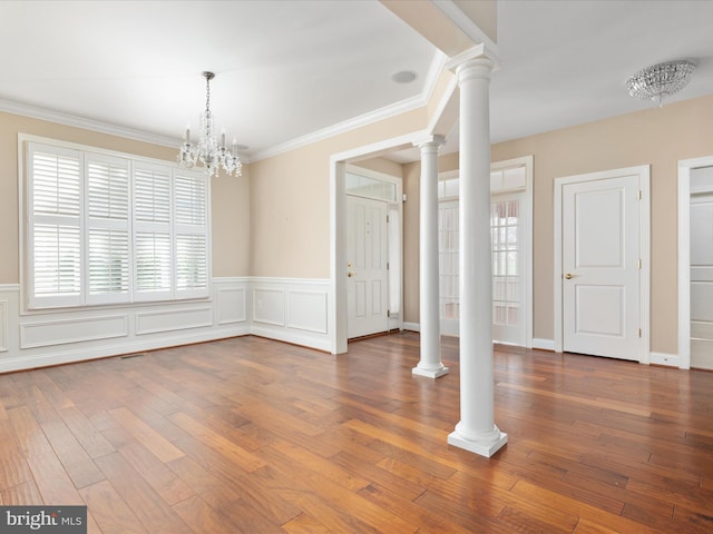 unfurnished dining area with a wealth of natural light, wood finished floors, decorative columns, and crown molding