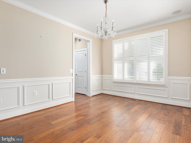 unfurnished room with visible vents, a chandelier, hardwood / wood-style floors, and ornamental molding