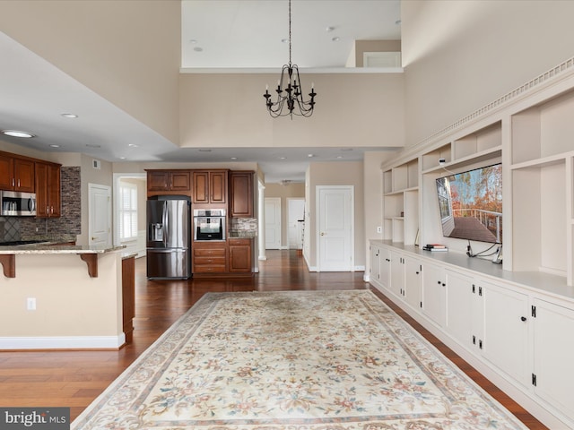 kitchen with a breakfast bar, dark wood-style flooring, open shelves, appliances with stainless steel finishes, and light stone countertops