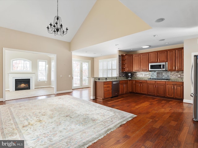 kitchen featuring dark wood-style floors, brown cabinets, stainless steel appliances, tasteful backsplash, and open floor plan