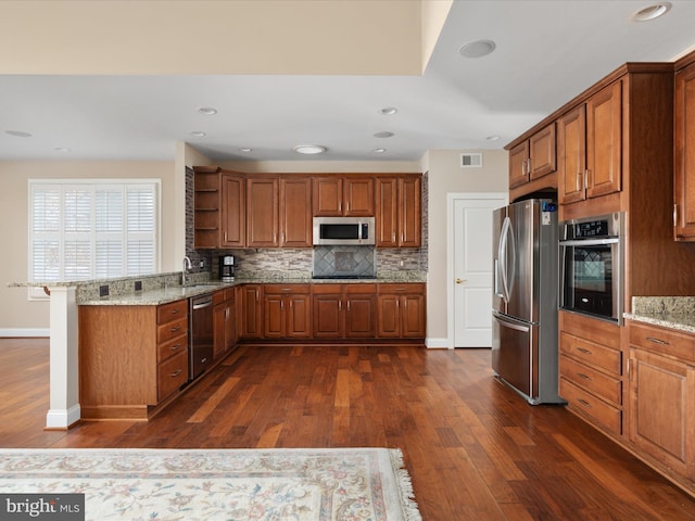 kitchen featuring brown cabinets, open shelves, stainless steel appliances, visible vents, and a peninsula