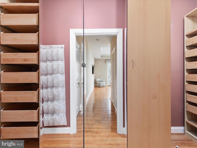 hallway featuring light wood-style flooring and baseboards