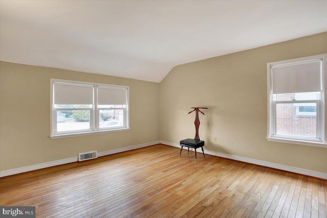 additional living space featuring lofted ceiling, light wood finished floors, baseboards, and visible vents