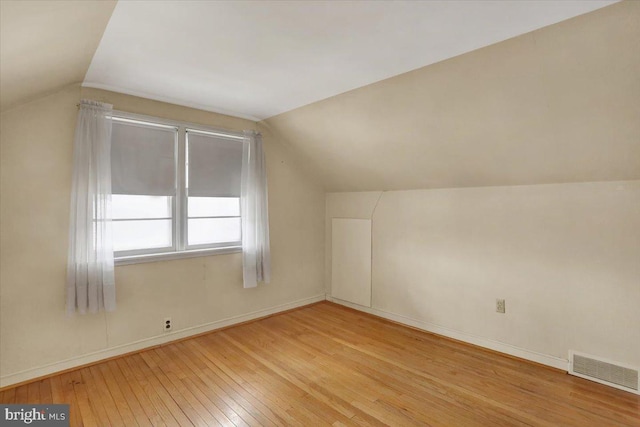 additional living space featuring vaulted ceiling, baseboards, visible vents, and light wood-style floors