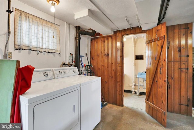 washroom featuring laundry area, separate washer and dryer, and wood walls