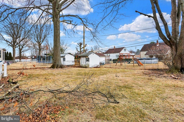 view of yard featuring a trampoline, a playground, a storage shed, fence, and an outdoor structure