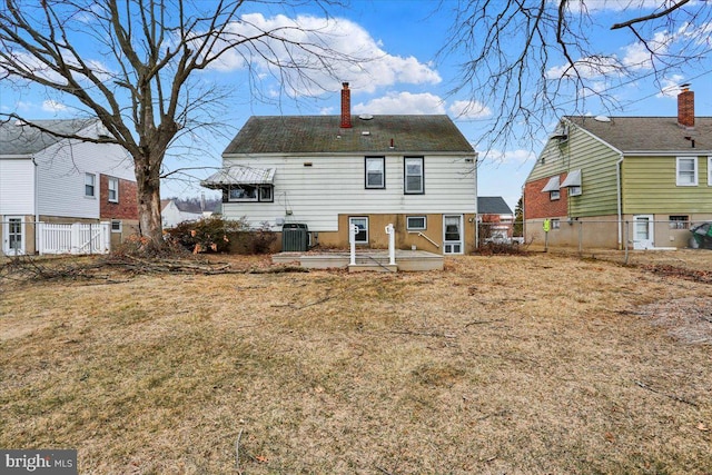 back of property with a yard, central AC unit, a chimney, and fence