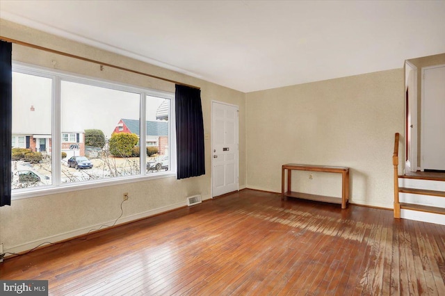 unfurnished room featuring baseboards, visible vents, and hardwood / wood-style floors