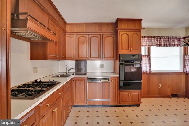 kitchen with stainless steel gas cooktop, black oven, a warming drawer, light floors, and paneled dishwasher