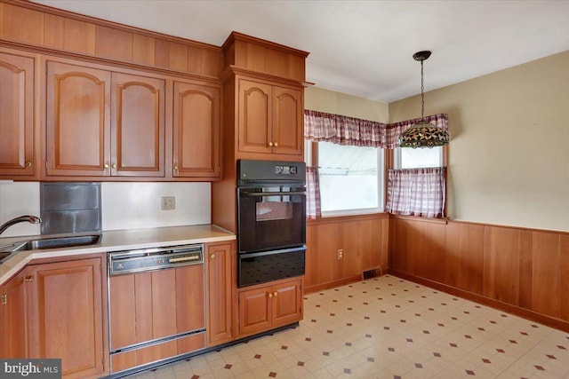 kitchen featuring oven, a warming drawer, a wainscoted wall, dishwasher, and light floors