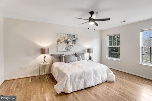 bedroom featuring visible vents, a ceiling fan, baseboards, and wood finished floors