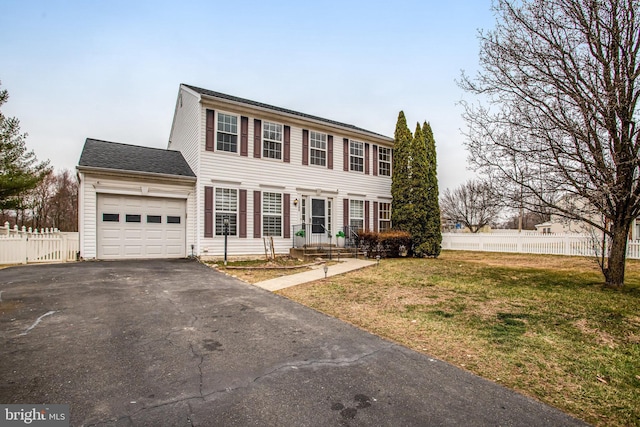 colonial-style house with a front yard, an attached garage, driveway, and fence