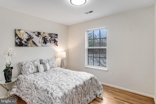 bedroom with light wood-type flooring, visible vents, and baseboards