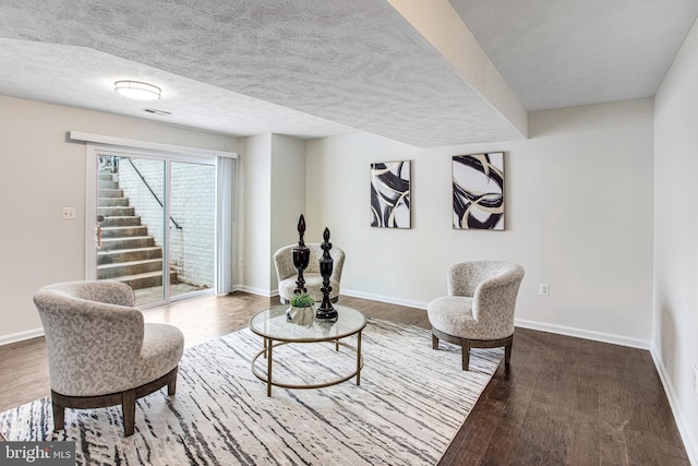 sitting room with baseboards, dark wood-style flooring, and a textured ceiling