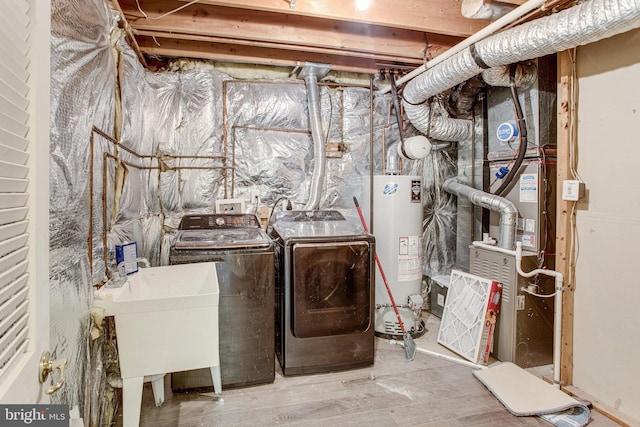 clothes washing area with water heater, laundry area, washing machine and dryer, and a sink