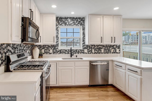 kitchen with a sink, stainless steel appliances, plenty of natural light, and a peninsula