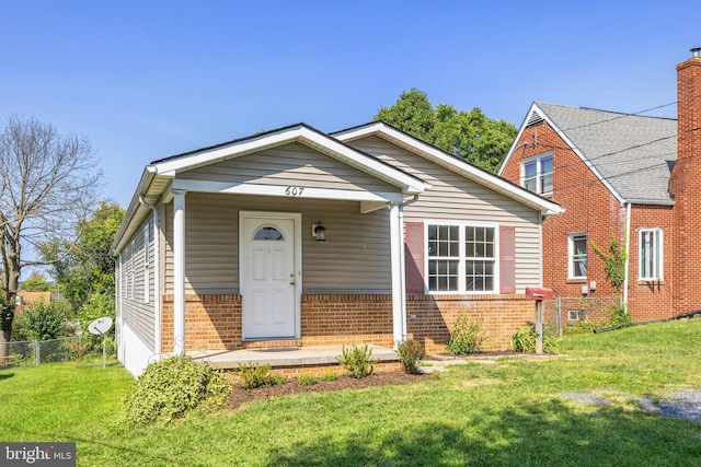 view of front of house with a front yard, brick siding, and fence