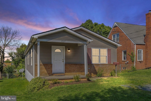 view of front facade with brick siding, a lawn, and fence