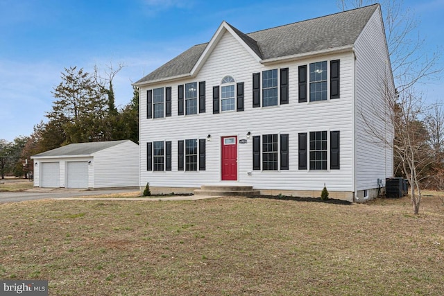 colonial-style house with a garage, a shingled roof, an outbuilding, central air condition unit, and a front yard