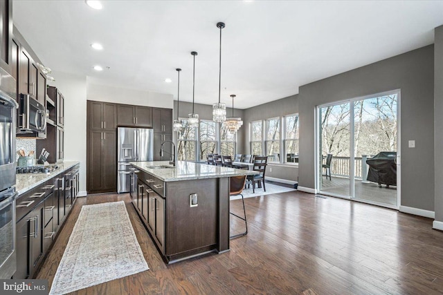 kitchen featuring a breakfast bar, dark brown cabinets, stainless steel appliances, and a sink