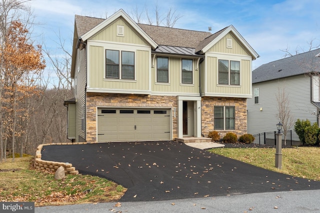 view of front facade with driveway, a standing seam roof, stone siding, a shingled roof, and a garage