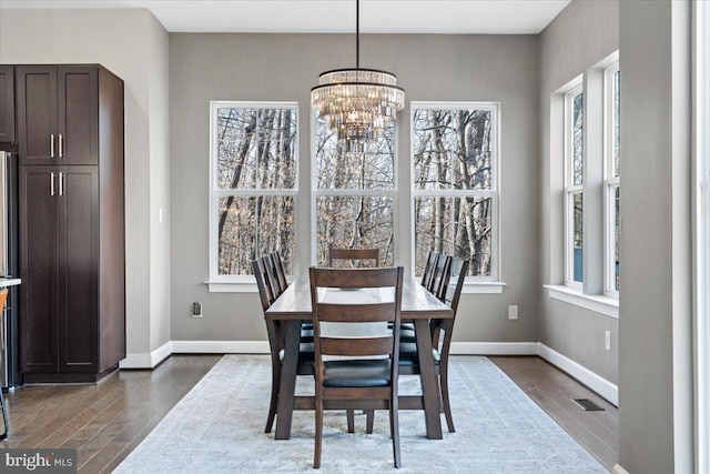 dining room featuring visible vents, baseboards, a notable chandelier, and dark wood-style flooring