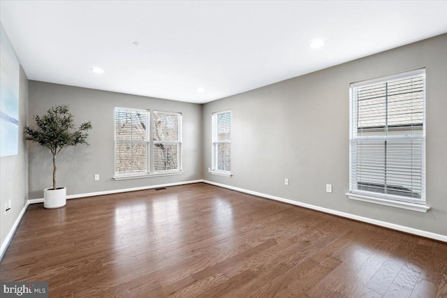 empty room featuring recessed lighting, baseboards, and dark wood-type flooring