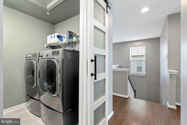 laundry room featuring wood finished floors, baseboards, laundry area, washer and dryer, and a barn door