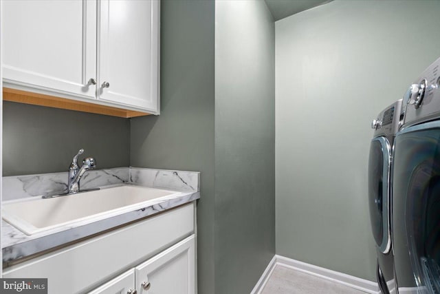 washroom with a sink, baseboards, cabinet space, and separate washer and dryer