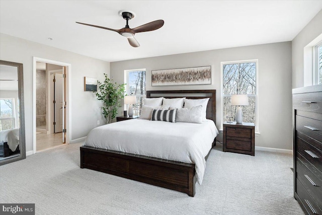 carpeted bedroom featuring connected bathroom, baseboards, multiple windows, and ceiling fan