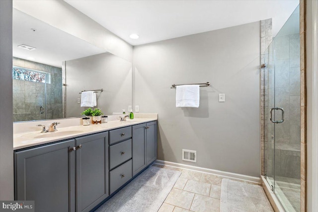 bathroom with a stall shower, baseboards, visible vents, and a sink