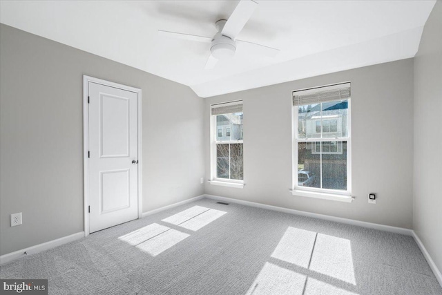 empty room featuring lofted ceiling, a ceiling fan, baseboards, and carpet floors