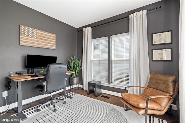 home office with wood finished floors, visible vents, and baseboards