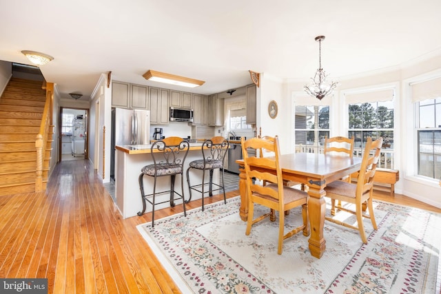 dining room with a wealth of natural light, light wood-type flooring, stairs, and an inviting chandelier