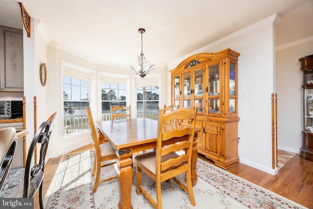 dining area featuring light wood finished floors, an inviting chandelier, baseboards, and ornamental molding